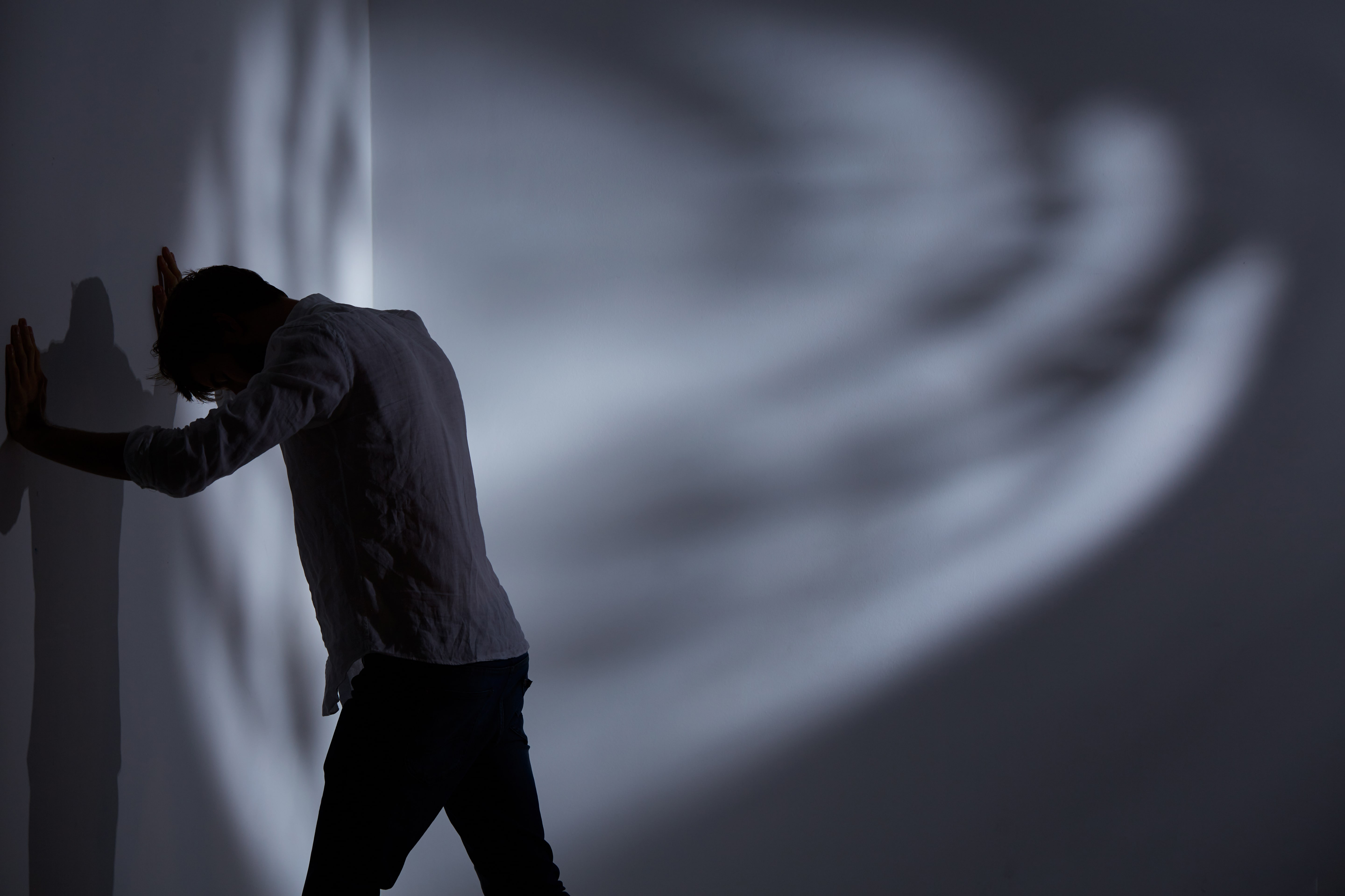 Person experiencing stress with hands against wall symbolising anxiety hypnotherapy Melbourne support and emotional healing
