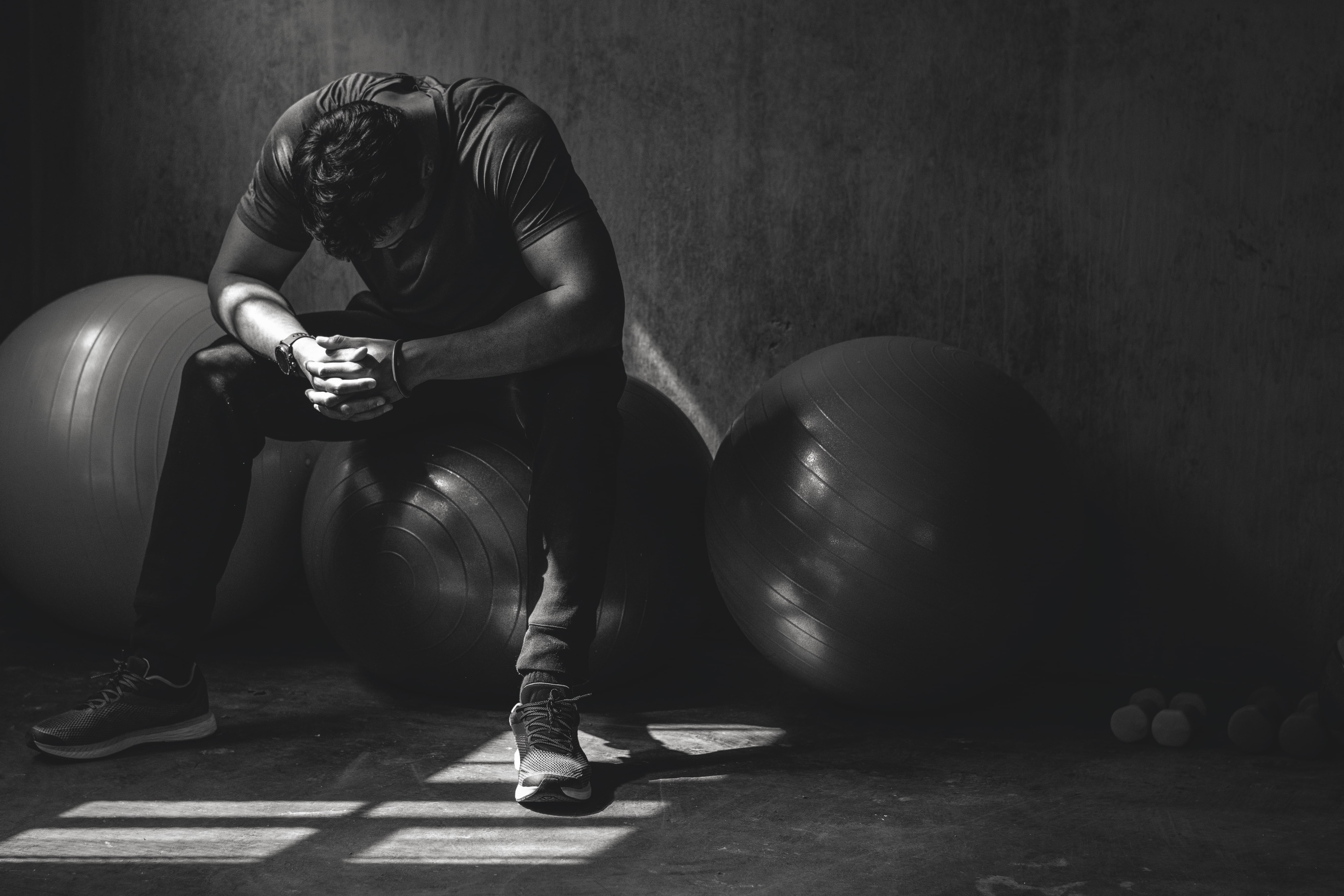 Man sitting with head down in gym showing signs of sadness and exhaustion related to depression symptoms